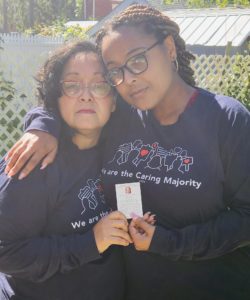 Rebekah and her mom, holding a funeral prayer card for her grandmother