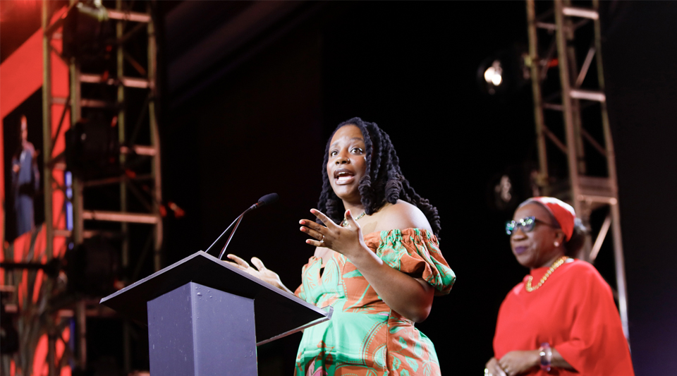 Care influencer Raena Boston delivers her acceptance speech at the Care Catalyst Awards ceremony. Tarana Burke stands behind her.