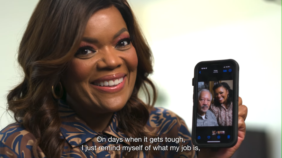 A still from the Council launch video, with Yvette Nicole Brown smiling and showing a photo of herself and her dad. The subtitle reads 