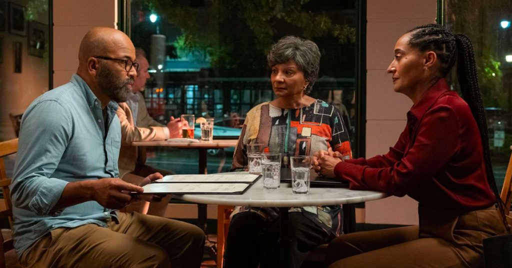 A scene from the movie 'American Fiction' of a son, mother, and daughter sitting at a restaurant. 