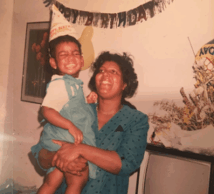 A photo of a mother holding her toddler during a birthday celebration.