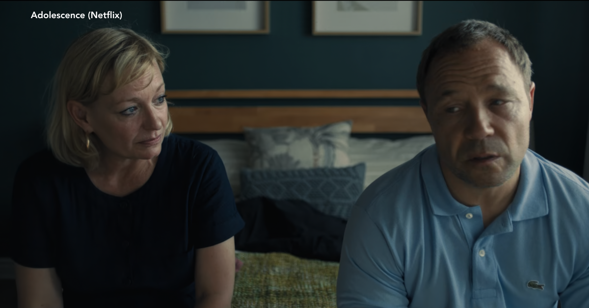 A man and woman sitting at the edge of a bed looking sorrow.