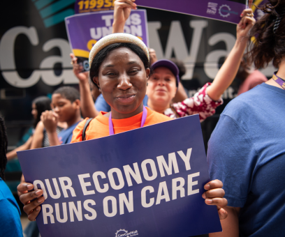A woman in a crowd holding a sign saying, 