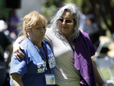 Two women embracing each other while attending a rally for care.