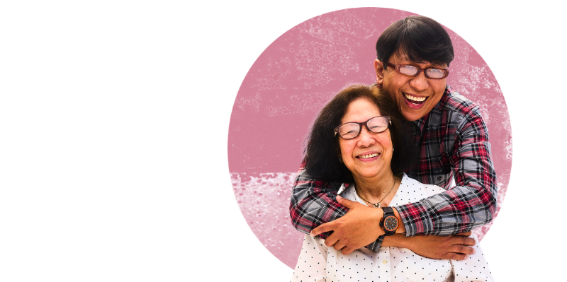 Image shows a man hugging his mother against a pink background