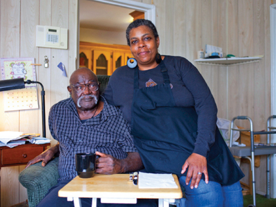A photo of a caregiver and an elderly man in his home.